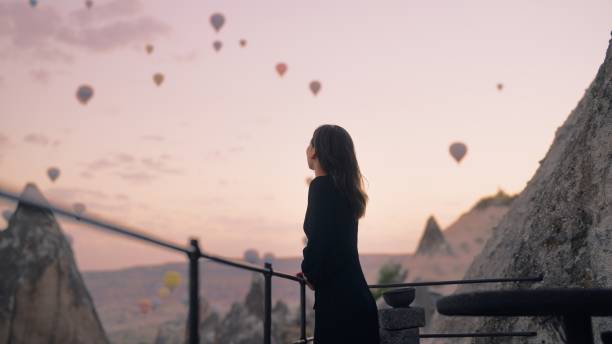 A female tourist enjoying watching hot air balloons flying in the sky