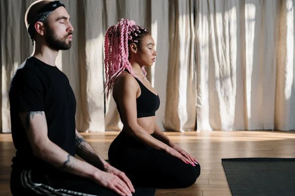 Young man and woman sitting in studio meditating