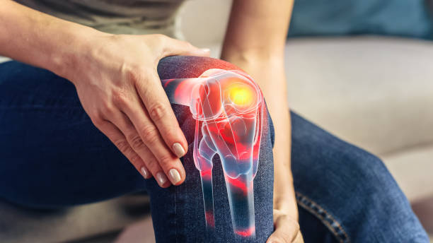 Young man sitting in sofa clutching his knee in pain, considering stem cells for knees treatment