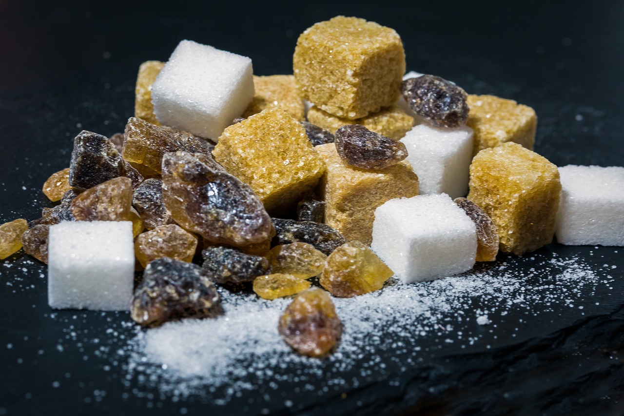 An assortment of sugar lumps and granulated sugars, illustrating how much sugar per day is commonly consumed.