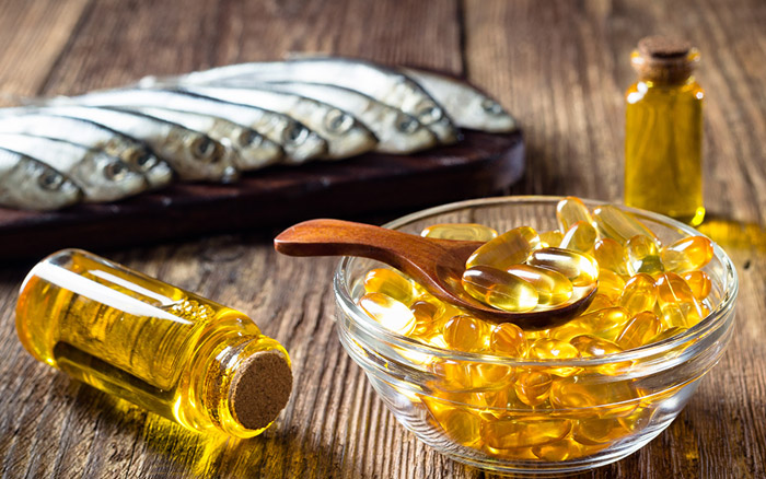 Fish oil supplements in a bowl with fresh fish in the background, highlighting the rich omega-3 source for brain, heart, and joint health.