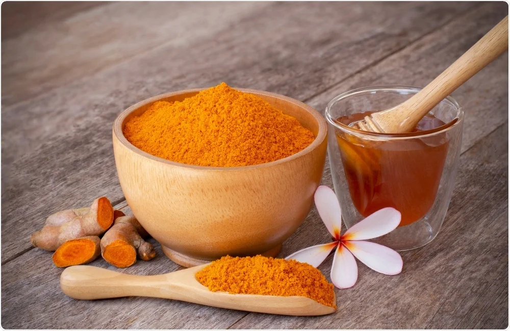 A bowl of vibrant curcumin turmeric powder with a bottle of liquid turmeric extract in the background, highlighting natural anti-inflammatory supplements.